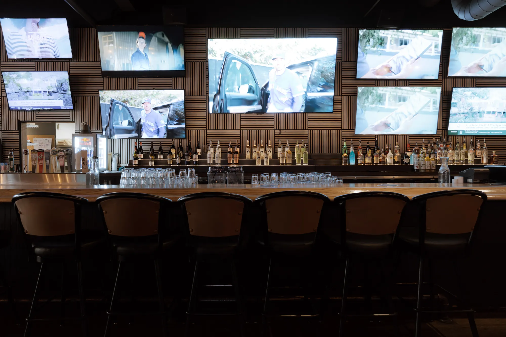 The bar with a wall of screens above the bottles