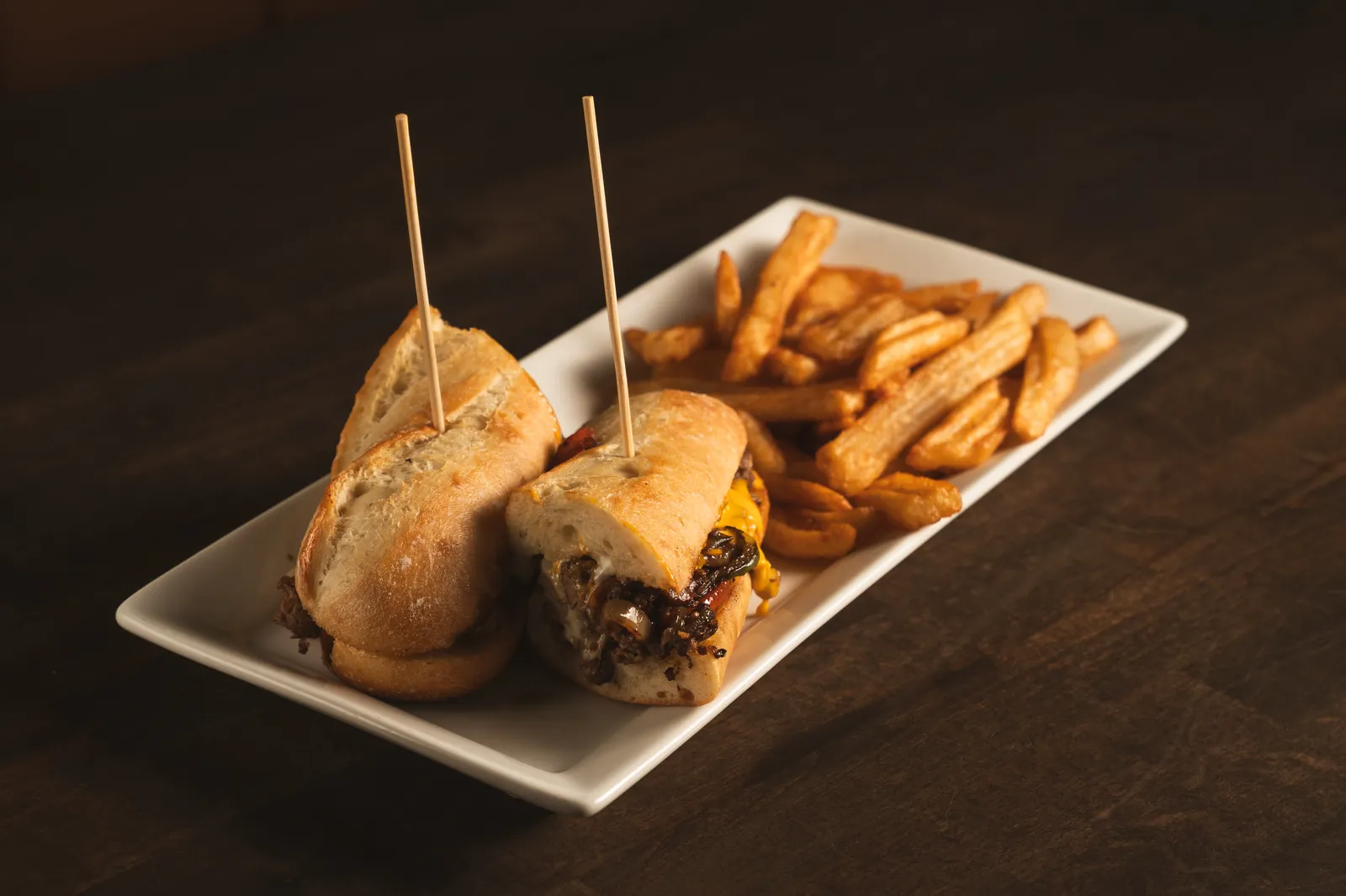 Philly cheesesteak on a baguette with fries