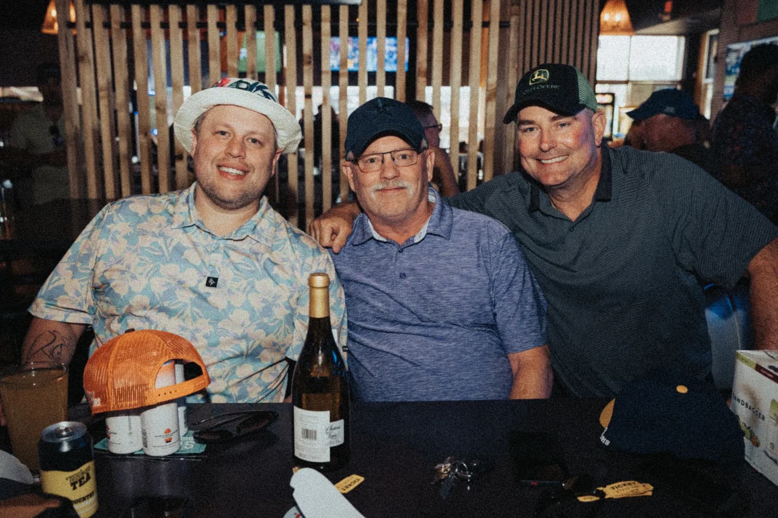 Three guests at the raffle table with a bottle of wine as a prize