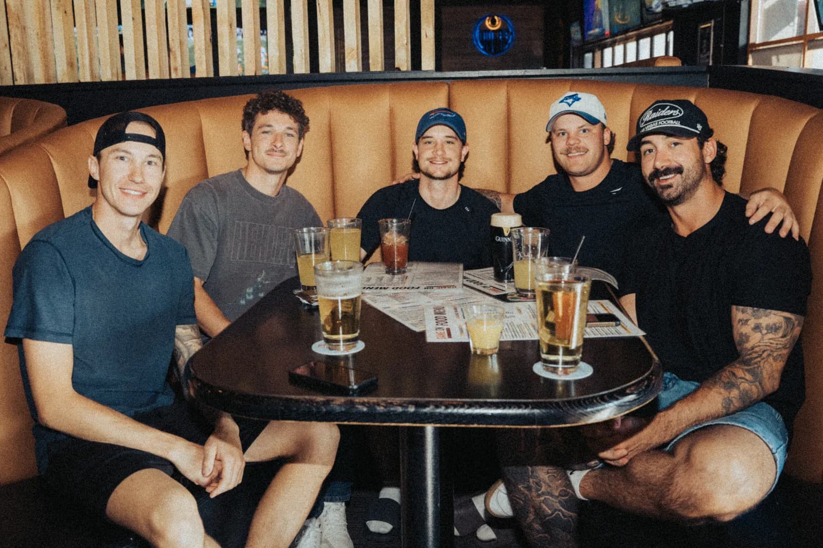 Five friends in a booth with pitchers on the table