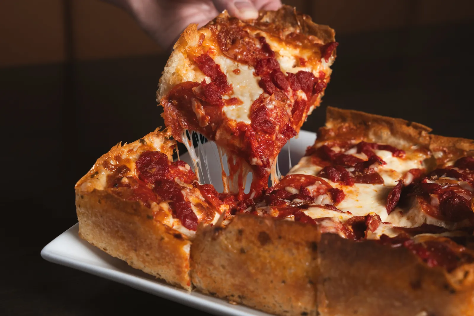 A square of Detroit style pizza lifted from the pan